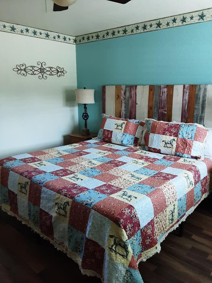 Bedroom with quilt, wooden headboard, turquoise and white walls, and a lamp.