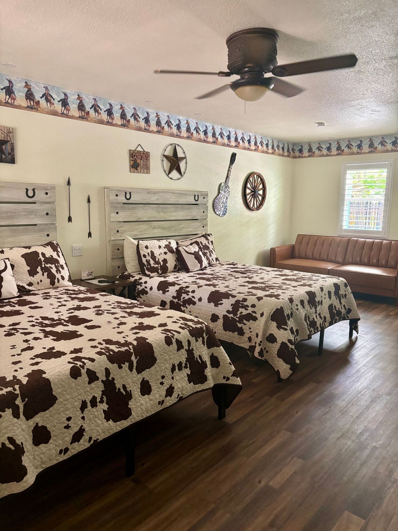 Western-themed bedroom with two beds, cowhide bedding, a couch, and decor.