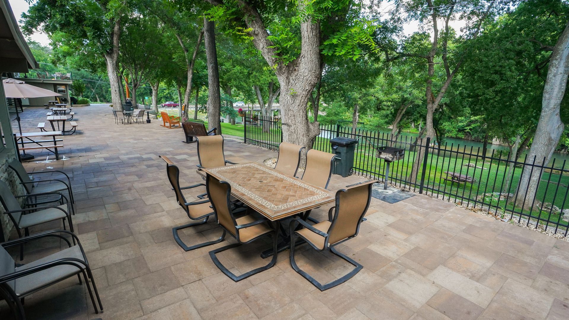 Patio with table and chairs, view of trees and fenced yard.